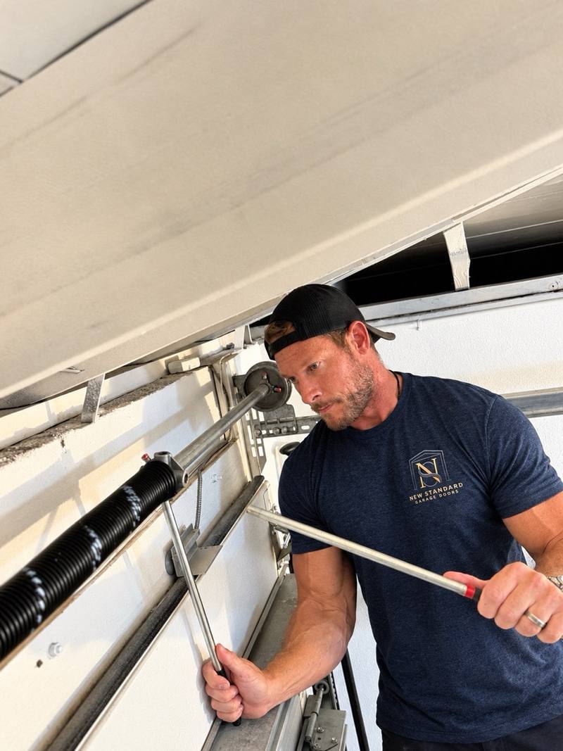 Matt winding a torsion spring with winding bars on a customer's garage door